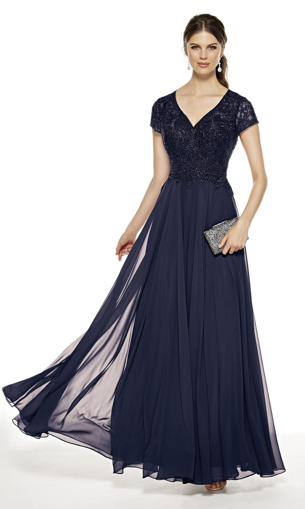 A woman wearing the Alyce 27389 long formal dress in navy, featuring a lace bodice, short sleeves, and a flowing chiffon A-line skirt, holds a small silver clutch.